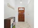 Bright entryway featuring tile flooring, a wooden door with glass panels, and a decorative storage unit at 2681 Debany Rd, Kissimmee, FL 34744