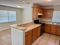 Well-lit kitchen featuring wooden cabinetry, granite countertops, tiled floors and modern appliances at 404 S Salisbury Ave, Deland, FL 32720