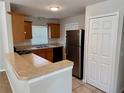 Functional kitchen with stainless steel refrigerator, matching cabinets, and breakfast bar with granite countertops at 404 S Salisbury Ave, Deland, FL 32720