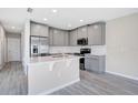 Well-equipped kitchen with stainless steel appliances, gray cabinetry, and a functional island for food prep at 4353 Campsite Loop, Orlando, FL 32824