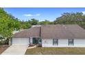 Single-story home featuring a two-car garage, neutral paint, well-maintained front yard, and lush surrounding trees at 4636 Fern Pine Dr, Orlando, FL 32808