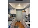 Cozy kitchen featuring stainless steel sink, white appliances, and wood flooring at 5964 Peregrine Ave # C02, Orlando, FL 32819