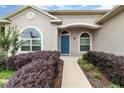Charming home featuring a blue front door, arched windows, and lush purple landscaping creating an inviting entrance at 11255 Se 170Th Pl, Summerfield, FL 34491