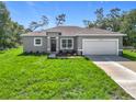 Charming single-story home with a gray exterior, green lawn, and a spacious two-car garage at 16253 Sw 29Th Court Rd, Ocala, FL 34473