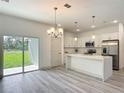 Stylish kitchen boasts white cabinets, stainless appliances, island, and sliding glass doors at 16253 Sw 29Th Court Rd, Ocala, FL 34473