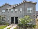 Modern townhome exterior featuring a stone facade, neutral stucco, and flowering tree at 1632 Tropical Palms Circle, Kissimmee, FL 34747