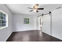 Bright bedroom with dark wood floors, ceiling fan, and sliding barn door at 1701 E Bay St, Winter Garden, FL 34787