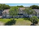 Exterior rear view of condo featuring green lawn and lush mature trees at 2216 Stonington Ave # 2216, Orlando, FL 32817