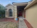 Inviting front entrance featuring a red door, decorative pillars, arched window, and lush landscaping at 2226 Newt St, Orlando, FL 32837