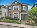 Charming two-story home featuring a manicured lawn, complemented by vibrant flowerbeds and a secure, decorative black metal fence at 473 Oviedo Blvd, Oviedo, FL 32765