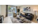 Bright living room with neutral walls, tile floors, modern furniture, and sliding glass doors leading to an outdoor space at 4731 Clock Tower Dr # 105, Kissimmee, FL 34746