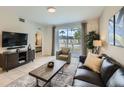 Comfortable living room featuring a dark leather sofa, accent chair, modern furniture, and outdoor view at 4731 Clock Tower Dr # 105, Kissimmee, FL 34746