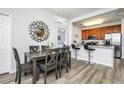 Dining area featuring wood-look floors and modern lighting adjacent to kitchen with breakfast bar at 4802 Cayview Ave # 301, Orlando, FL 32819
