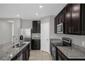 Modern kitchen with stainless steel appliances, granite countertops, and dark wood cabinets at 523 Tortugas St, Haines City, FL 33844