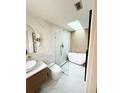 Sleek bathroom showcasing a glass enclosed shower and a freestanding tub beneath a skylight at 7813 Delphia St, Orlando, FL 32807