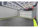 Spacious garage featuring modern lighting, a checkered floor, and overhead storage racks for optimal organization at 8436 Tavistock Lakes Boulevard, Orlando, FL 32827