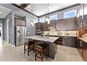 Stylish kitchen with stainless steel appliances, a marble island with seating, and dark wood cabinetry at 8436 Tavistock Lakes Boulevard, Orlando, FL 32827