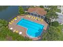 Community pool with inviting blue water, surrounded by lounge chairs, umbrellas, and lush landscaping at 2447 Hassonite St, Kissimmee, FL 34744