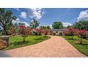 Charming single-story home featuring a brick driveway, lush lawn, and vibrant flowering trees enhancing curb appeal at 2491 Island Dr, Longwood, FL 32779