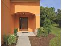 A welcoming front entrance with a dark wood door, manicured bushes and mulched flower bed at 2660 Santosh Cv, Kissimmee, FL 34746