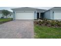 Charming home featuring an attached two-car garage, landscaped yard, and brick paver driveway at 5158 Gardenrow Dr, St Cloud, FL 34772