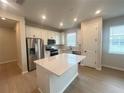 Modern kitchen featuring white cabinets, stainless steel appliances, a kitchen island, and wood flooring at 5158 Gardenrow Dr, St Cloud, FL 34772