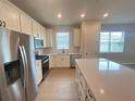 Bright kitchen featuring white cabinets, stainless steel appliances, a kitchen island, and wood flooring at 5158 Gardenrow Dr, St Cloud, FL 34772
