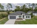 Charming single-story home features a gray garage door, white exterior, and well-maintained front yard at 6054 Sw 154Th Place Rd, Ocala, FL 34473