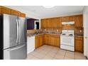 Functional kitchen with stainless steel refrigerator, white appliances and oak cabinets at 715 Wedge Ln, Poinciana, FL 34759