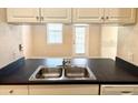 Galley kitchen features a stainless steel double sink, black counter, and white cabinets at 860 N Orange Ave # 371, Orlando, FL 32801