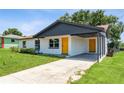 Bright single-story home with a modern carport, fresh white paint, and an eye-catching yellow front door at 1105 Valencia Ave, Haines City, FL 33844