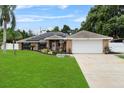 Inviting single-story home with lush green lawn, complemented by a brick facade and two-car garage at 157 Ambergate Ct, Debary, FL 32713