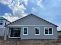Rear exterior featuring gray siding, white window trim, covered patio, and sliding glass doors for natural light at 5250 Teirgarten St, St Cloud, FL 34771