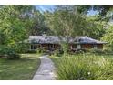 Beautiful single-story brick home with a landscaped yard, mature trees, and a walkway to the entrance at 628 Riverpark Cir, Longwood, FL 32779