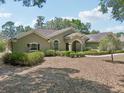 Well-maintained home featuring lush landscaping, a manicured lawn, and a circular driveway at 6686 Se 135Th St, Summerfield, FL 34491