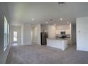 Bright, open-concept living area with gray carpet flooring seamlessly connecting to a modern kitchen with white cabinets at 1392 Dalkeith Cv, Sanford, FL 32771