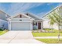Charming single-story home featuring a gray facade, well-maintained landscaping, and an attached two-car garage at 26271 Feathergrass Cir, Leesburg, FL 34748