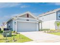 Single-story home featuring a gray facade, well-maintained landscaping, and a two-car garage at 26271 Feathergrass Cir, Leesburg, FL 34748