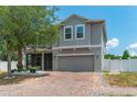 Charming two-story home features a brick driveway, attached garage, screened in porch, and a well-maintained yard at 275 Lakeshore Dr, Davenport, FL 33837