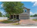 Charming two-story home features a brick driveway, attached garage, screened in porch, and a well-maintained yard at 275 Lakeshore Dr, Davenport, FL 33837