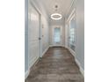 Bright hallway features wood floors, decorative front door and a stylish chandelier light fixture at 275 Lakeshore Dr, Davenport, FL 33837