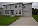 Inviting two-story home featuring a well-maintained lawn, attached garage, and neutral gray color scheme at 4905 Pall Mall E St, Kissimmee, FL 34758