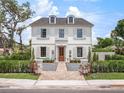 Stunning white two-story home featuring symmetrical design, shuttered windows, and a charming brick pathway at 541 W Canton Ave, Winter Park, FL 32789