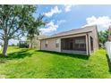 Spacious backyard featuring lush green grass, a screened-in porch, and mature trees at 6728 Duncaster St, Windermere, FL 34786