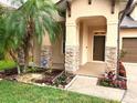 Inviting front entrance with stone accents, mature landscaping, and a secure ADT system at 6728 Duncaster St, Windermere, FL 34786