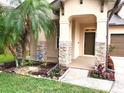 Inviting front porch featuring stacked stone accents, lush landscaping and a welcoming entrance at 6728 Duncaster St, Windermere, FL 34786
