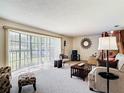 A sunlit living room with plush carpet, cozy seating, and large windows at 721 Fairway Dr, New Smyrna Beach, FL 32168