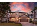 Charming two-story home with well-manicured lawn, stone accents and two-car garage, set against a colorful sunset sky at 8180 Valhalla Ter, Reunion, FL 34747