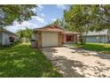 Single-story house with a brick facade, attached garage, and well-kept lawn, shaded by mature trees at 916 Glendale St, Orlando, FL 32807