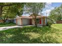 Single-story home with brick accents, bright red door, and landscaped front yard with large shady tree at 916 Glendale St, Orlando, FL 32807